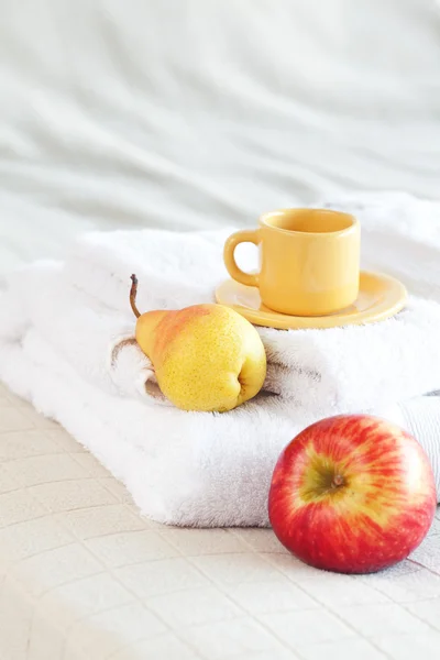 Чашка чая, яблоко и груша на кровати — стоковое фото
