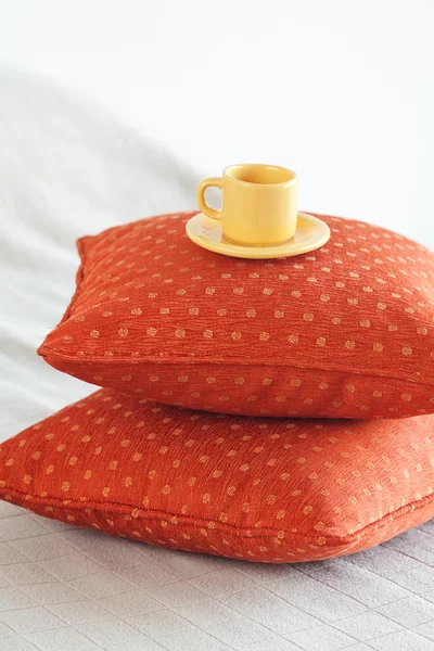 Чашка, лежащая на подушках на кровати — стоковое фото