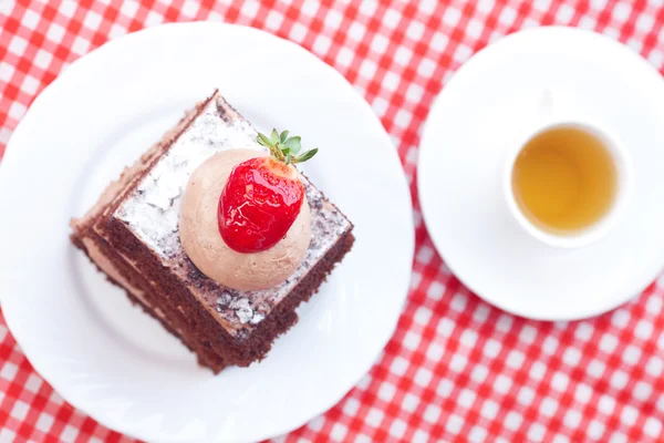 Hermoso pastel con fresa y té en tela a cuadros — Foto de Stock