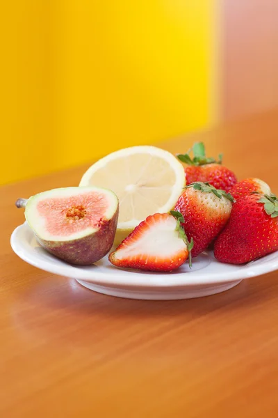 Limón, higo y fresas en un plato —  Fotos de Stock