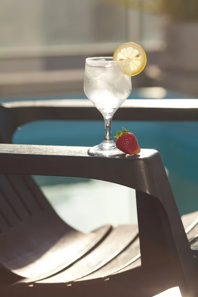 Swimming pool, lounge, a wine glass with ice, lemon and strawber — Stock Photo, Image