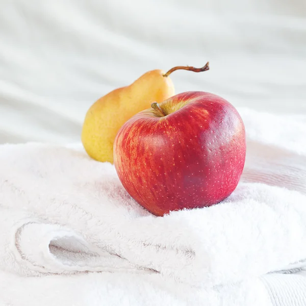 Manzana y pera sobre toallas en la cama — Foto de Stock
