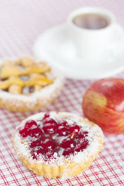 Hermoso pastel con bayas, manzana y té en tela a cuadros —  Fotos de Stock