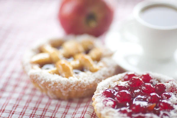 Hermoso pastel con bayas, manzana y té en tela a cuadros —  Fotos de Stock