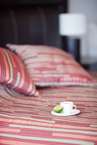 Кровать с двумя подушками, чашка чая на одеяле — стоковое фото
