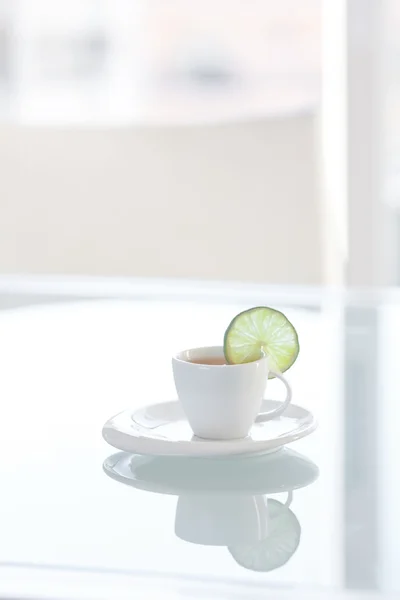 Tasse Tee mit Zitrone auf einer Glasoberfläche — Stockfoto