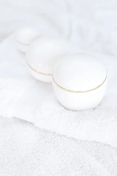 Kosmetiska behållare liggande på vit handduk — Stockfoto