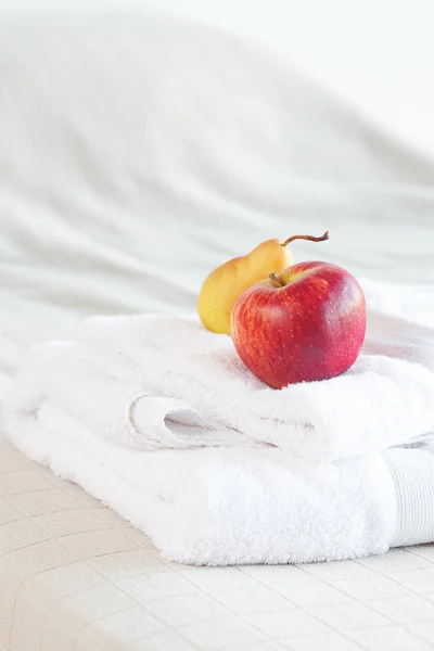 Яблоко и груша на полотенцах на кровати — стоковое фото