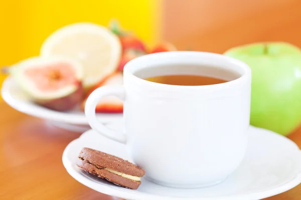 Tasse Tee, Kekse, Apfel, Zitrone, Feige und Erdbeeren auf einem Teller — Stockfoto