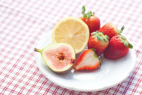 Limão, figo e morangos em um prato — Fotografia de Stock