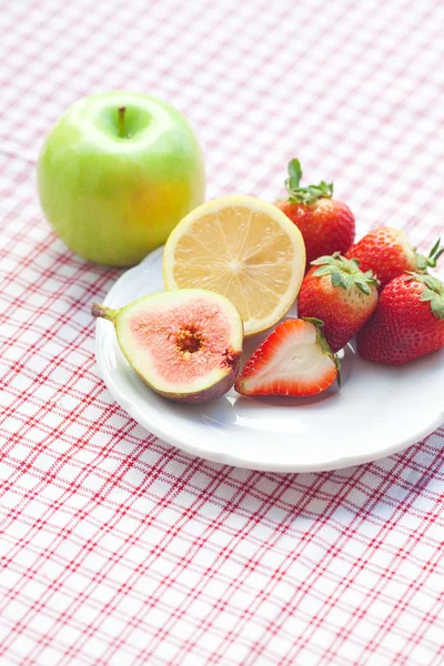 Maçã, limão, figo e morangos em um prato — Fotografia de Stock