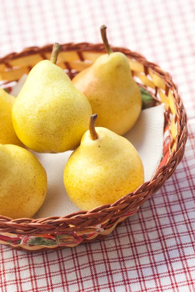 Pears in a wooden basket lying on a plaid fabric — Stock Photo, Image