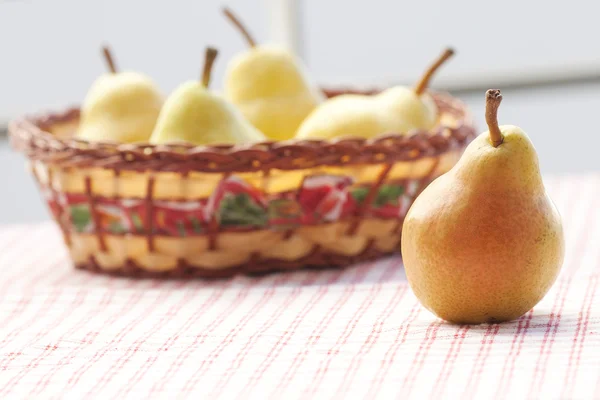 Päron i trä korg liggande på ett rutigt tyg — Stockfoto
