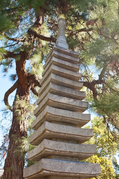 Каменная пагода на фоне зеленых деревьев — стоковое фото