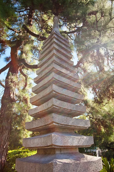 Каменная пагода на фоне зеленых деревьев — стоковое фото