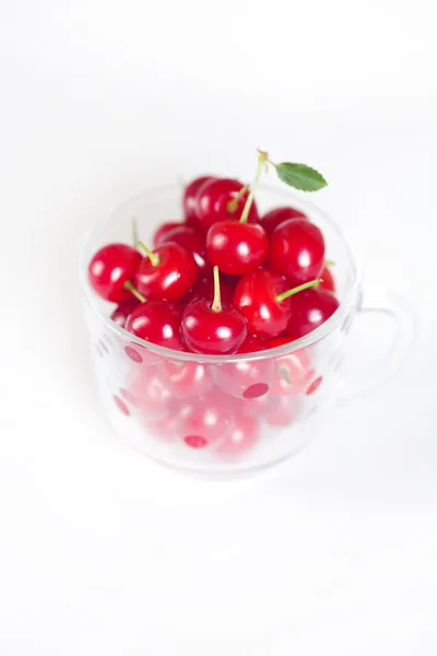 Cereza con hoja verde y una taza de cerezas sobre un fondo blanco —  Fotos de Stock