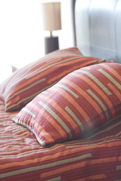 Cama com travesseiro, mesa de cabeceira e lâmpada — Fotografia de Stock