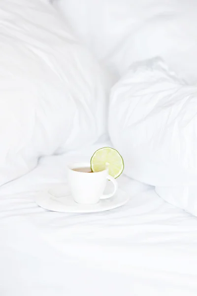 Postel s polštáři a šálek čaje — Stock fotografie