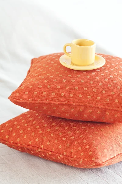 Taza acostada sobre almohadas en la cama — Foto de Stock