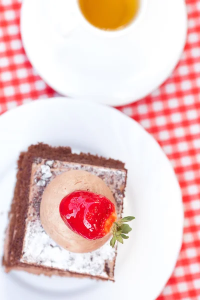 Vacker tårta med jordgubbar och te på rutigt tyg — Stockfoto