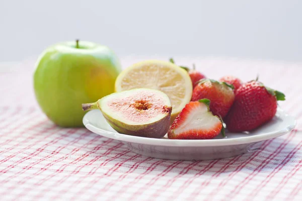 Maçã, limão, figo e morangos em um prato — Fotografia de Stock