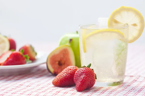 Cocktail with ice,lemon, fig and strawberries on a plate — Stock Photo, Image