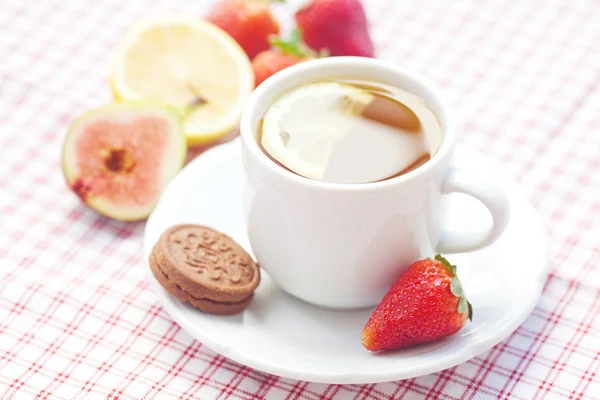 Чашка чая, печенья, инжира и клубники на тарелке — стоковое фото