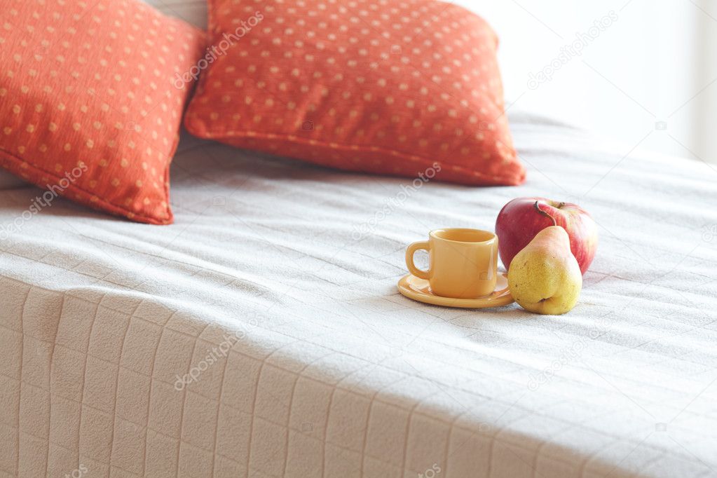 Cup of tea,apple and pear on the bed