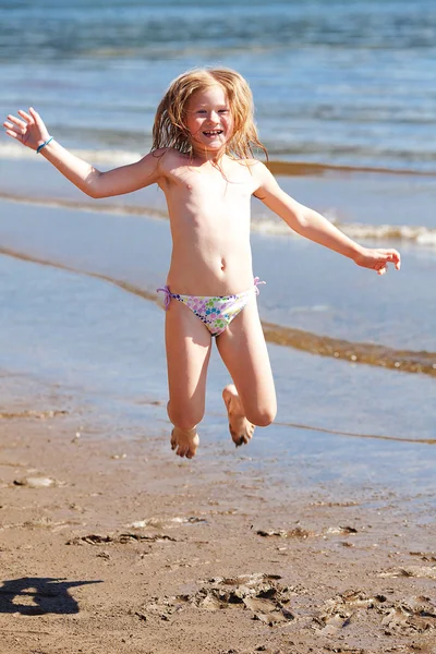 漂亮的小女孩，在沙滩上跳跃 — 图库照片