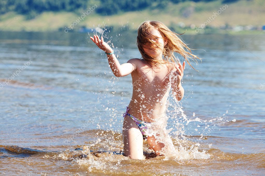 Schönes kleines Mädchen planscht im Wasser.