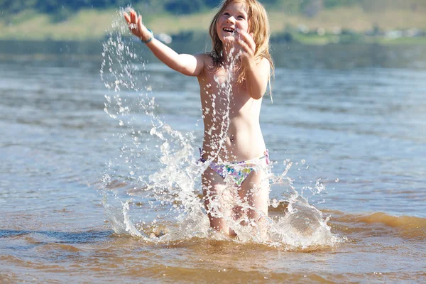 Beautiful little girl splashes in the water — Stock Photo, Image