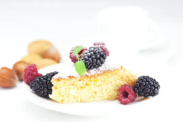 Coupe, gâteau, framboise, mûre, noix et menthe sur une assiette sur un w — Photo