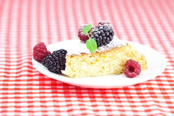 Торт з глазур'ю, малиною, ожиною та м'ятою на тарілці на плиті — стокове фото