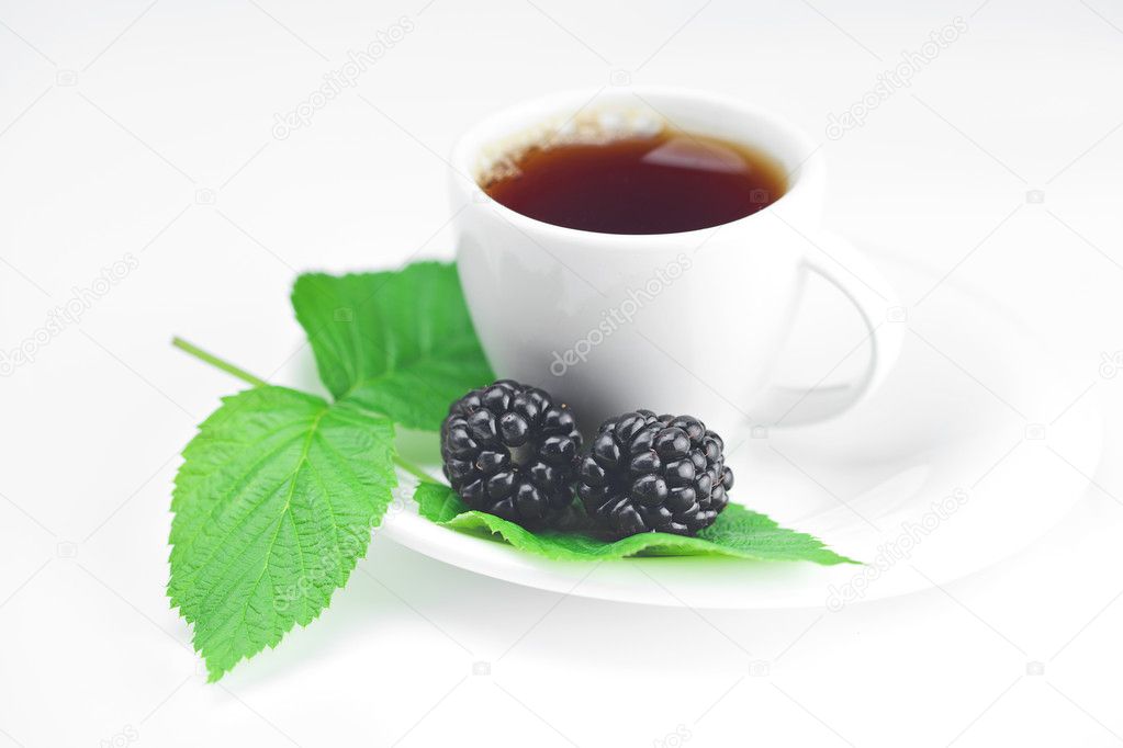 Cup of tea and blackberry with leaves on white background