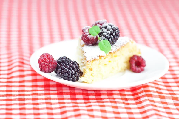 Торт з глазур'ю, малиною, ожиною та м'ятою на тарілці на плиті — стокове фото