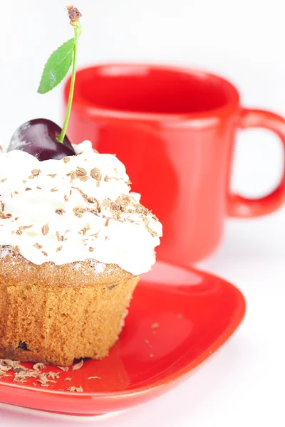 Muffin con crema batida, cerezas y taza roja sobre fondo blanco —  Fotos de Stock