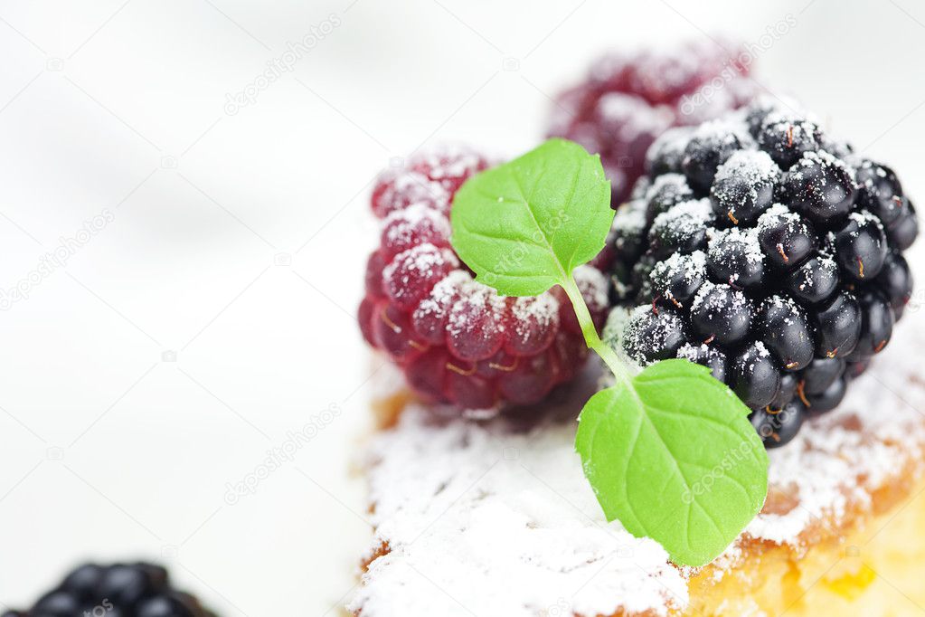 Cake, raspberry, blackberry,nuts and mint on a plate on a white
