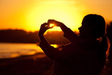 Little girl holding in hands the setting sun