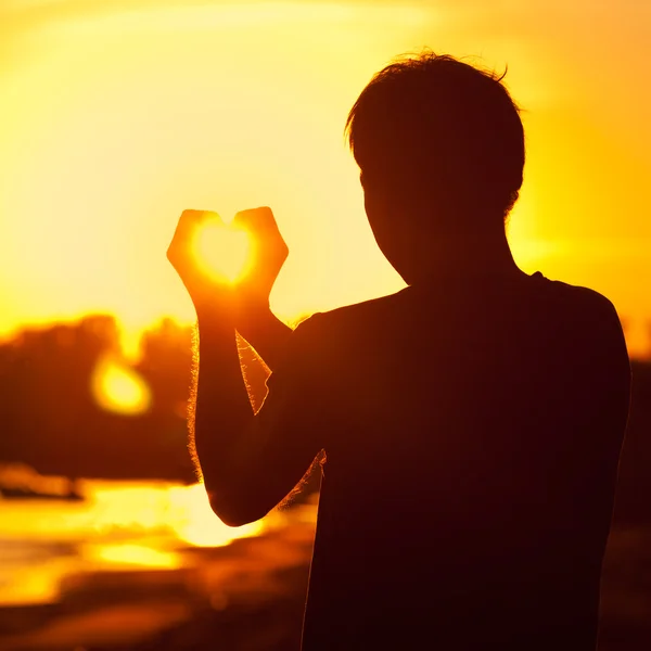 Молодой человек, держащий в руках заходящее солнце — стоковое фото