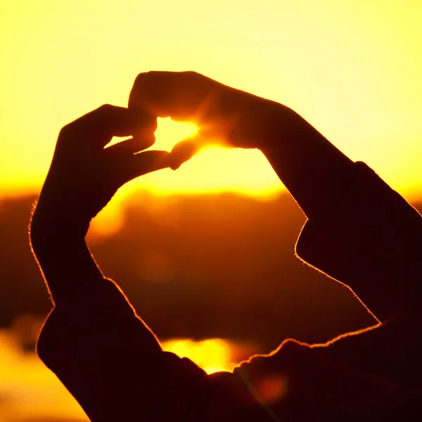 Liten flicka håller i händer den nedgående solen — Stockfoto