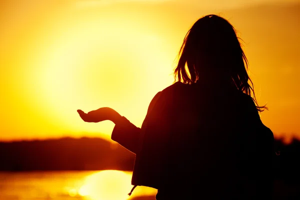 Little girl holding in hands the setting sun — Stockfoto