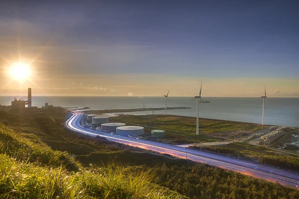 Uma estrada e moinhos de vento durante o pôr do sol — Fotografia de Stock