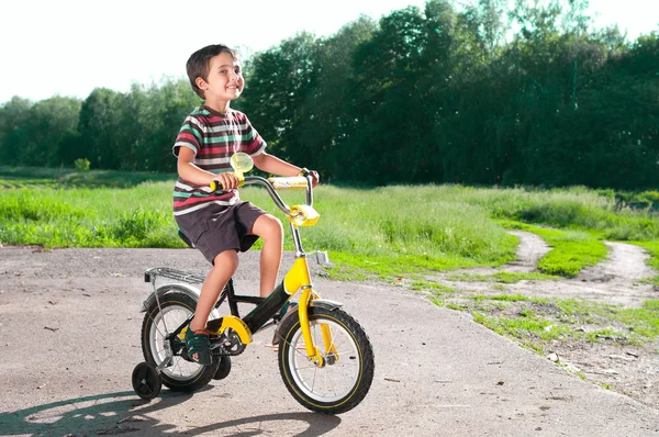 Kleine jongen rijden fiets op landweg buitenshuis — Stockfoto