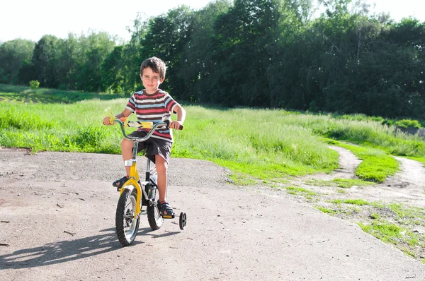 Malý kluk na koni kolo na venkovské silnici venku — Stock fotografie