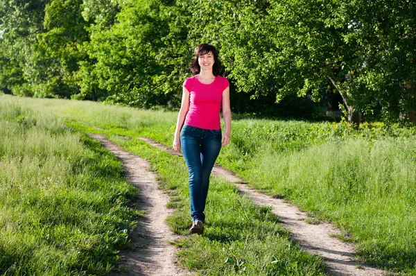 Usmívající se žena chůze venku na lesní cestě — Stock fotografie