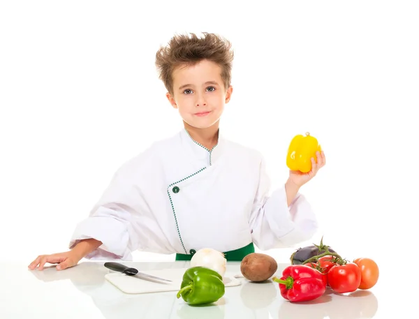 Kleine jongen chef-kok in uniform met mes koken vegatables bedrijf — Stockfoto