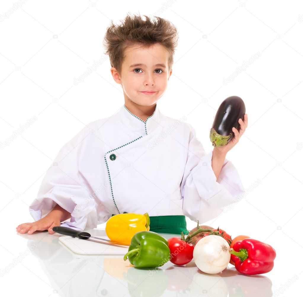 Little boy chef in uniform with knife cooking vegatables holding