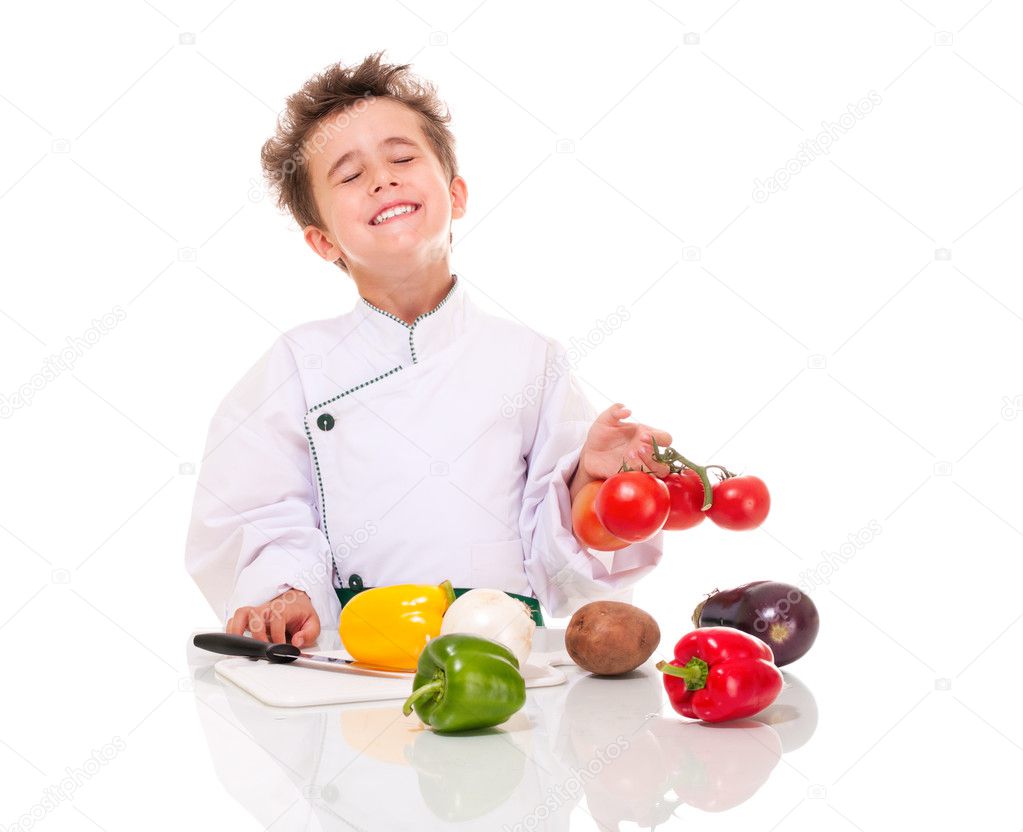 Little boy chef in uniform with knife cooking vegatables holding