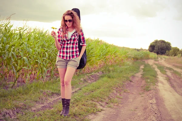 Young redhead woman with guitar passes corn field outdoors in su — Stock Photo, Image