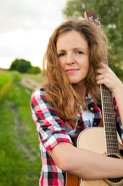 Young redhead woman holding guitar outdoors in summer — Stock Photo, Image